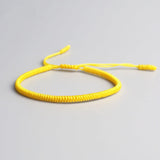 Bracelet tibétain porte-bonheur jaune sur sol gris Kaosix
