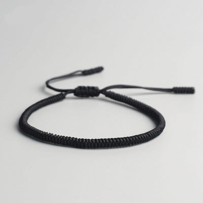 Bracelet tibétain porte-bonheur noir sur sol gris Kaosix