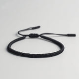 Bracelet tibétain porte-bonheur noir sur sol gris Kaosix