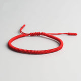 Bracelet tibétain porte-bonheur rouge sur sol gris Kaosix 
