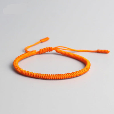 Bracelet tibétain porte-bonheur orange sur sol gris Kaosix