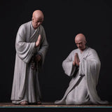 Deux Statues Moines Bouddhistes Humilité et Respect Debout Blanc Genoux Gris sur fond noir Kaosix