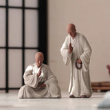Deux Statues Moines Bouddhistes Humilité et Respect Debout Blanc Lotus Blanc sur fond Beige et flou Kaosix
