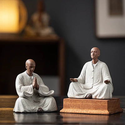 Deux Statues Moines Bouddhistes Prière et Méditation posés sur une table en bois avec un arrière plan flou kaosix