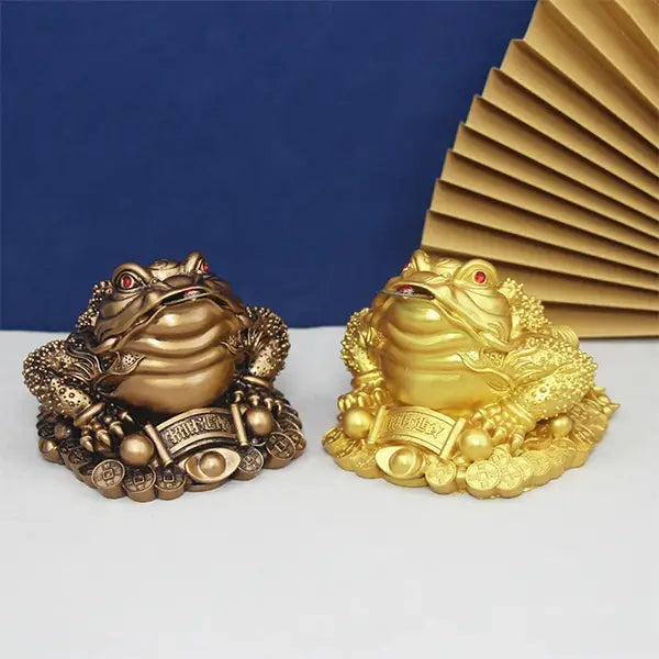 Deux Statuettes Jin Shan Crapaud d’Argent Feng Shui pour attirer la prospérité or et bronze sur un sol blanc et un fond bleu kaosix