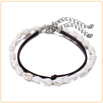 Double bracelet de cheville en coquillages buccin et cordon de cuir sur fond blanc Kaosix