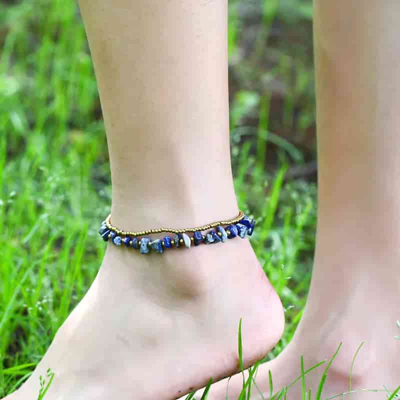 Double bracelet de cheville en éclats de lapis-lazuli et perles de cuivre à la cheville d'une jeune femme kaosix