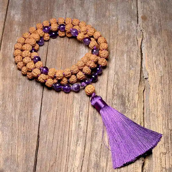 Mala 108 perles Graine de Rudraksha Améthyste avec Pompon posé sur un parquet en bois Kaosix