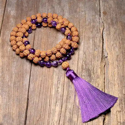 Mala 108 perles Graine de Rudraksha Améthyste avec Pompon posé sur un parquet en bois Kaosix