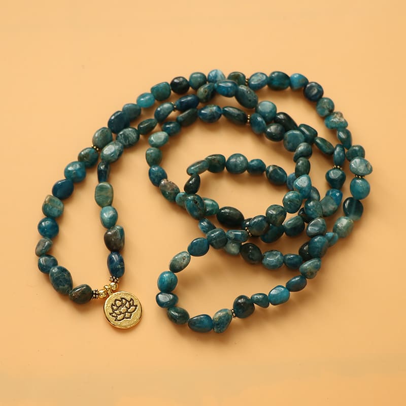 Mala 108 perles Apatite Bleue Symbole du Lotus deroulé et posé sur un sol de couleur orange Kaosix