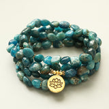 Mala 108 perles Apatite Bleue Symbole du Lotus posé sur un sol de couleur beige Kaosix