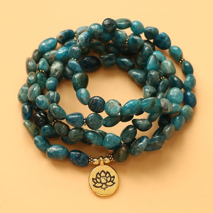 Mala 108 perles Apatite Bleue Symbole du Lotus posé sur un sol de couleur orange Kaosix