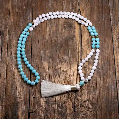 Mala 108 perles howlite blanche et turquoise Pompon sur un parquet en bois et vue de dessus Kaosix