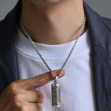 Pendentif porte-bonheur tibétain mantra Om accroché au cou d'un homme Kaosix