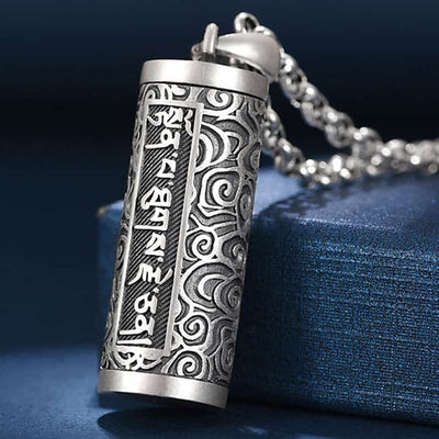 Pendentif porte-bonheur tibétain mantra Om posé contre un socle bleu Kaosix