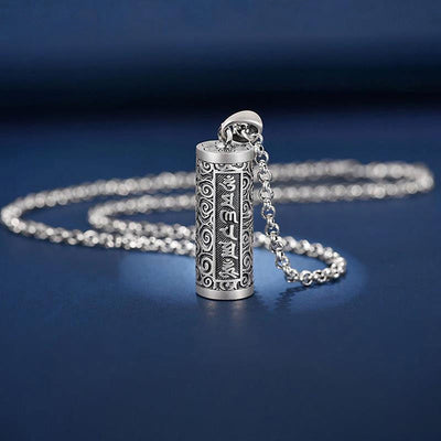 Pendentif porte-bonheur tibétain mantra Om posé sur un sol bleu et vue de loin Kaosix