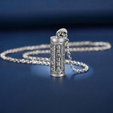 Pendentif porte-bonheur tibétain mantra Om posé sur un sol bleu et vue de loin Kaosix