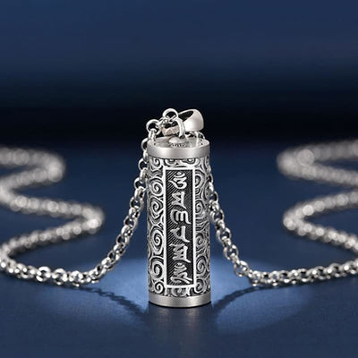 Pendentif porte-bonheur tibétain mantra Om posé sur un sol bleu et vue en gros plan Kaosix