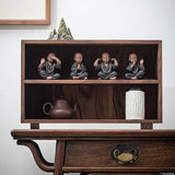 Quatre Statues de Moines Tibétains Compagnons de Sérénité posés horizontalement dans une petite armoire chinoise posée sur une table en bois kaosix