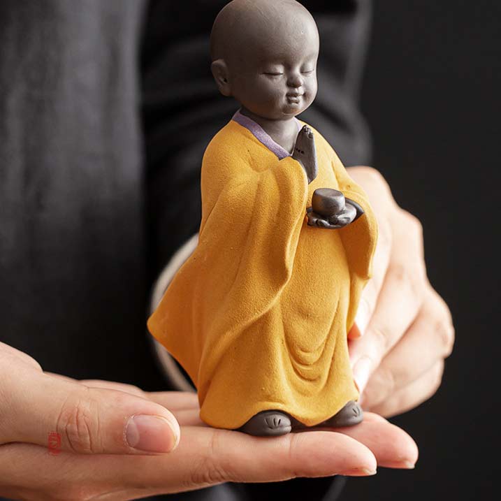 Statue Moine Tibétain debout jaune en position verticale dans la main d'un homme Kaosix