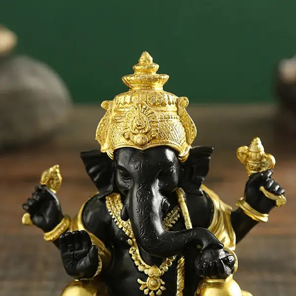 Statue de Ganesh doré sur table en bois vue de face gros plan sur la tête kaosix