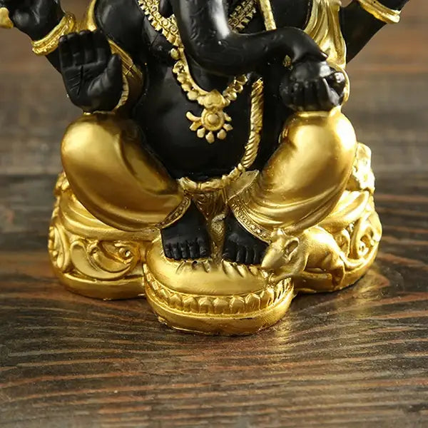 Statue de Ganesh doré sur table en bois vue de face gros plan sur les pieds kaosix