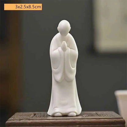 Statue moine bouddhiste zen céramique blanche pose anjali mudra assis sur banc en bois et fond gris Kaosix 3