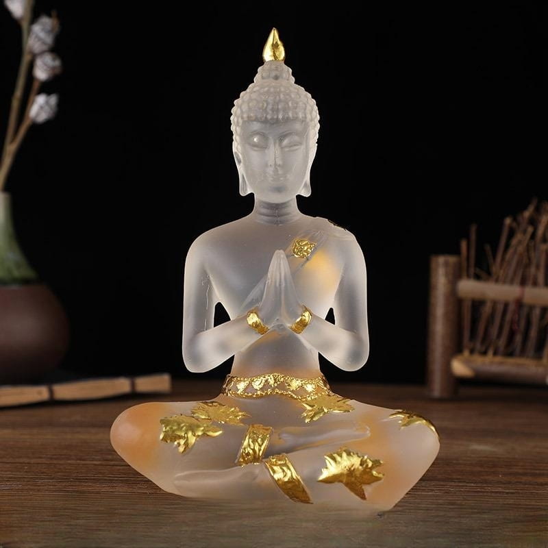 Statuette de Bouddha en résine translucide blanc assis de face sur une table en bois et un fond noir Kaosix