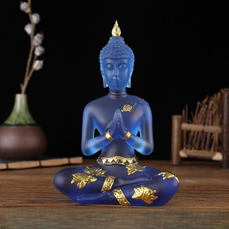 Statuette de Bouddha en résine translucide bleu assis de face sur une table en bois et un fond noir Kaosix