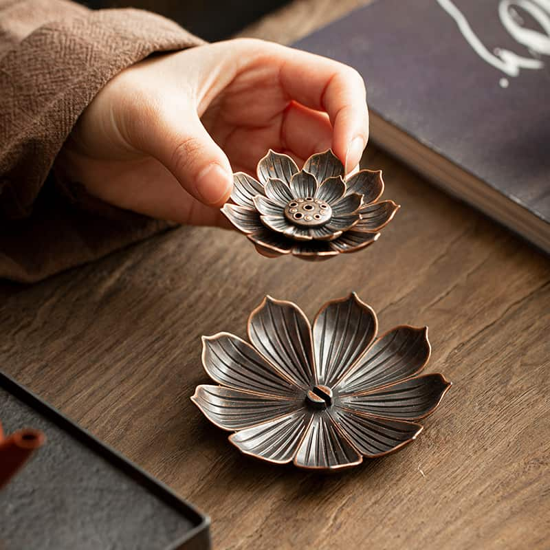 une main de femme qui tient la partie amovible du Porte Encens Fleur De Lotus Bronze pour montrer comment le nettoyer Kaosix