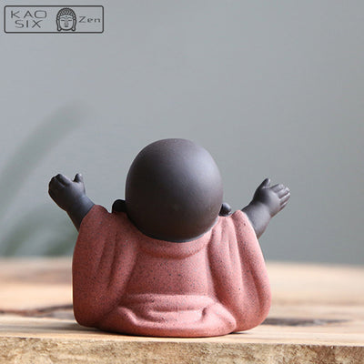 statuette bouddha rieur fortune robe orange vue de dos assis sur une table en bois kaosix