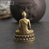 Statue Bouddha de la médecine vue de dos et posé sur une table avec une grosse tête de Bouddha en fond kaosix