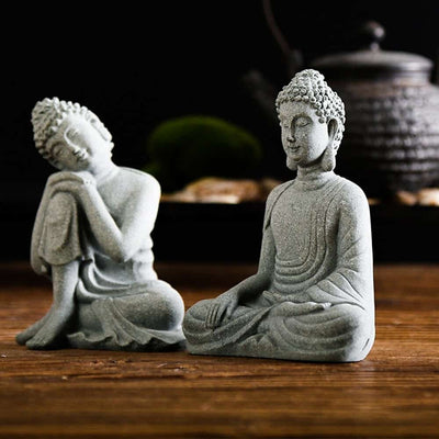 2 Statues de Bouddha assis appel à la terre et penseur posés sur une table en bois avec fond noir Kaosix