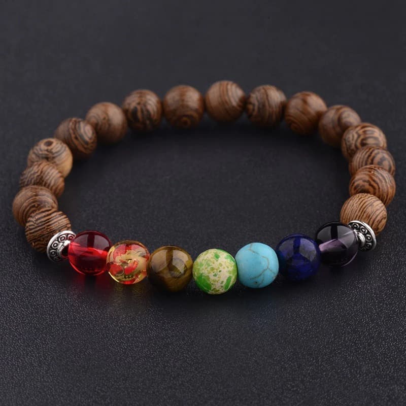 Bracelet 7 chakras méditation perles de bois posé sur table noire Kaosix