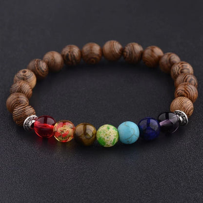 Bracelet 7 chakras méditation perles de bois posé sur table noire Kaosix