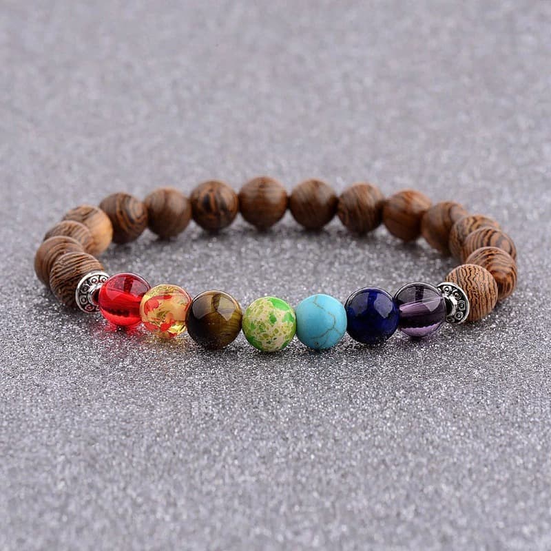 Bracelet 7 chakras méditation perles de bois posé sur tapis gris Kaosix