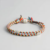 Bracelet Bouddha porte bonheur jaune et rouge tête de bouddha moulin à prières sur fond gris 1 Kaosix