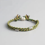 Bracelet Bouddha porte bonheur vert tête de bouddha moulin à prières sur fond gris Kaosix