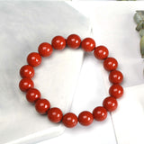Bracelet Jaspe Rouge clarté posé à moitié sur une plaque de marbre blanche et à moitié sur une nappe de table Kaosix
