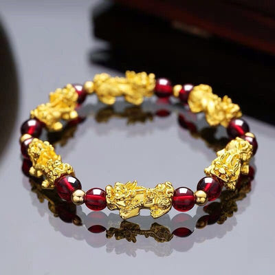 Bracelet Pi Xiu Grenat Rouge posé sur une table en verre gris Kaosix