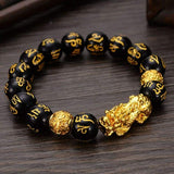 Bracelet Pi Xiu Or en obsidienne noire Mani Mantra sur table en bois Kaosix
