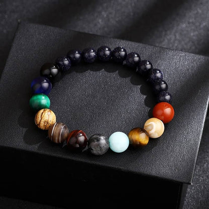 Bracelet Système Solaire avec 11 Planètes en Perles de Pierres posé sur une boite noire Kaosix