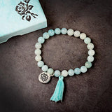 Bracelet amazonite verte symbole lotus sur un sol en ciment sombre Kaosix