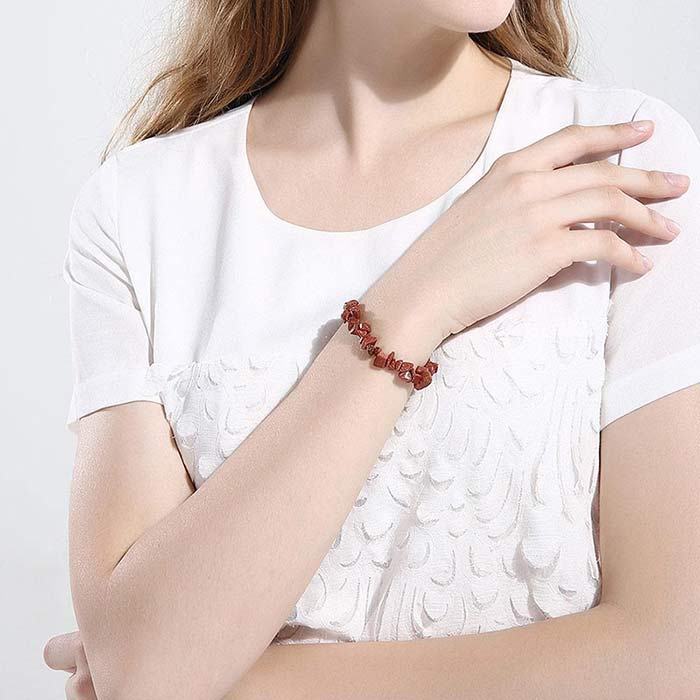 Bracelet baroque (chips) grès rouge au poignet d'une jeune fille habillée de blanc Kaosix