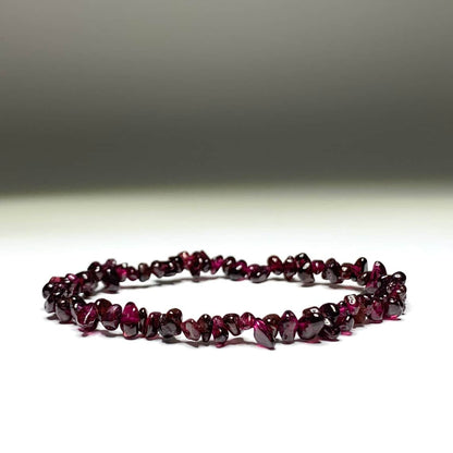 Bracelet baroque chips grenat rouge posé sur un sol blanc et avec un fond gris Kaosix