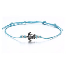 3 bracelets de cheville avec amulette tortue de mer en métal argenté et cordon bleu blanc ou noir sur sol blanc Kaosix