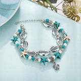 Bracelet de cheville en coquillages cauris étoiles de mer avec amulette tortue de mer sur une table bleue Kaosix