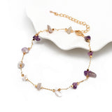 Bracelet de cheville en éclats de pierre d’améthyste et chaînette dorée sur le rebord d'une assiette blanche Kaosix