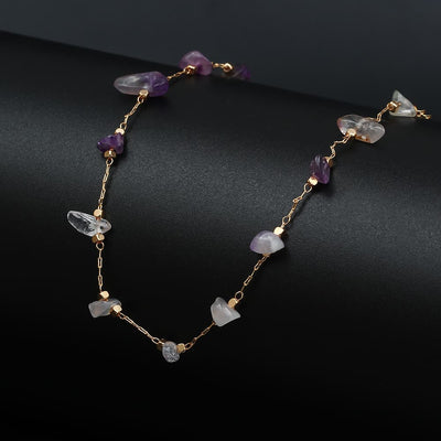 Bracelet de cheville en éclats de pierre d’améthyste et chaînette dorée sur un socle noir Kaosix