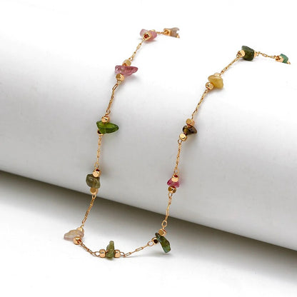 Bracelet de cheville en éclats de pierre de tourmaline et chaînette dorée sur socle blanc Kaosix